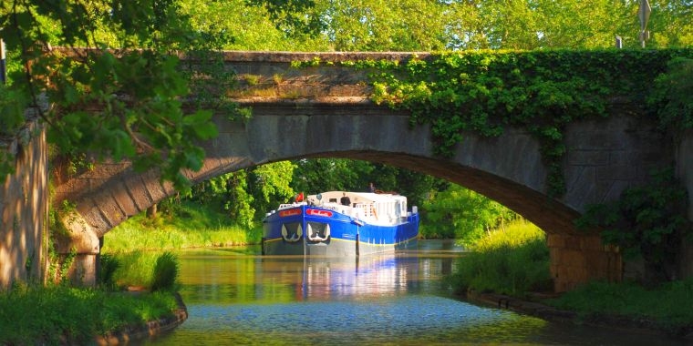 El "Enchante" navegando bajo un puente del Canal du Midi CRUCEROS FLUVIALES CANALES DE FRANCIA ENCHANTE FAMILIAS CRUCEEROS